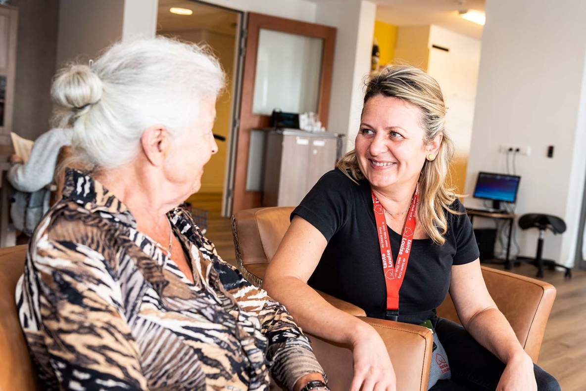 Verzorgende in gesprek bewoner van tanteLouise