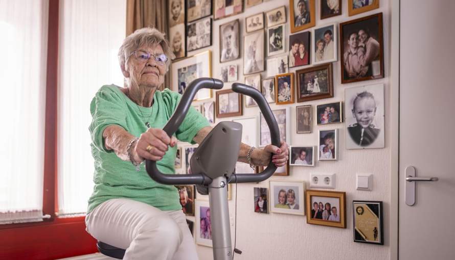 Senior is actief bezig op een hometrainer in haar woning.