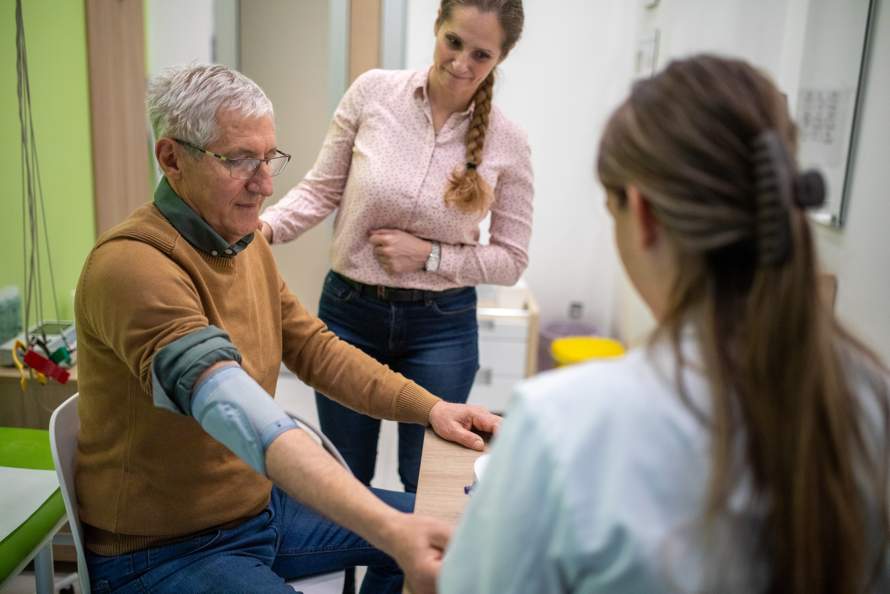 Verpleegkundige meet bloedruk bij mannelijke cliënt